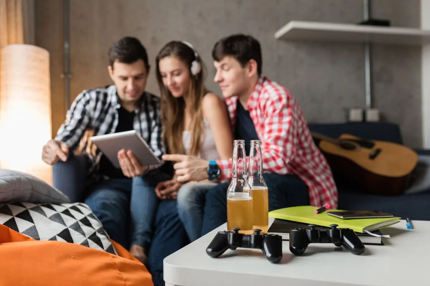 Счастливые молодые люди используют планшет, студенты учатся, веселятся, домашняя вечеринка друзей, хипстерская компания вместе, двое мужчин и одна женщина, улыбаются, позитивные, онлайн-обучение, слушают музыку